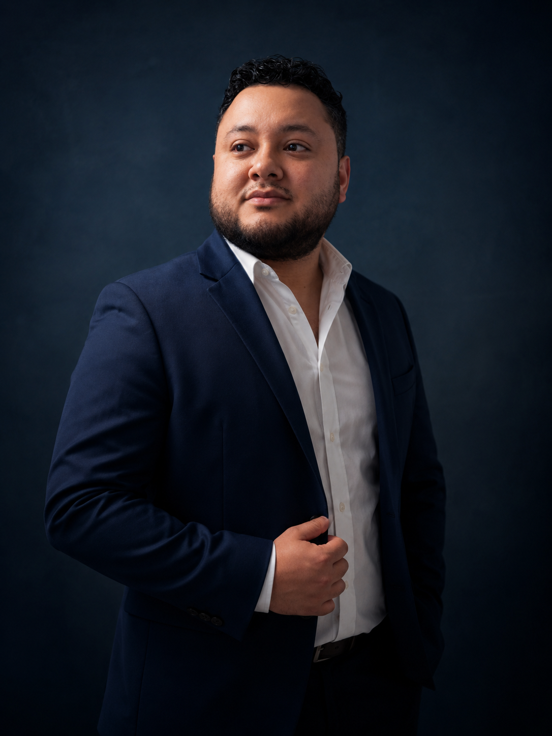 Chris Mandujano con saco azul sobre fondo azul